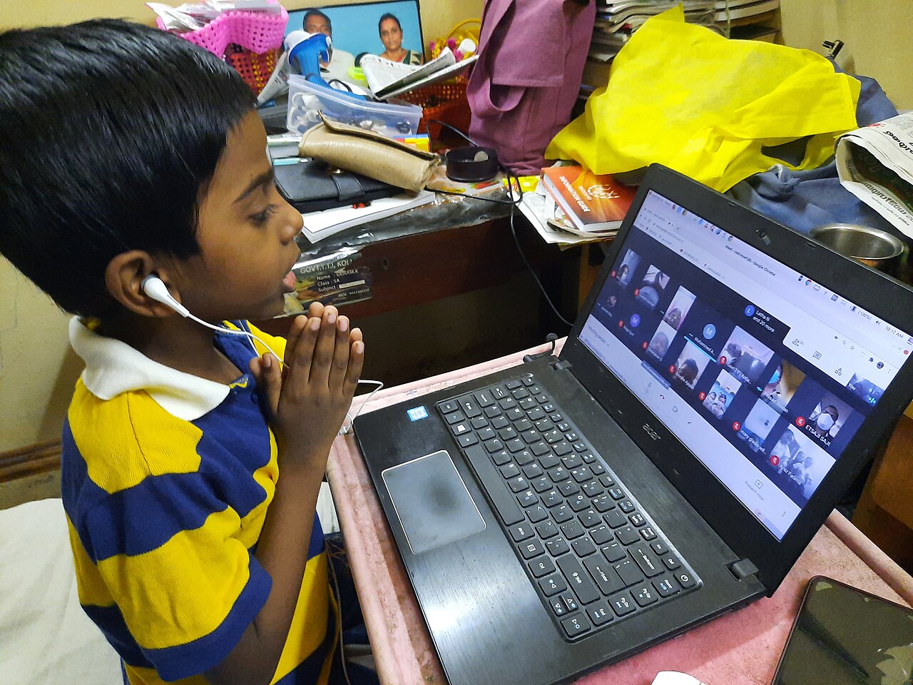 An Indian student attending an online class from home on a laptop
